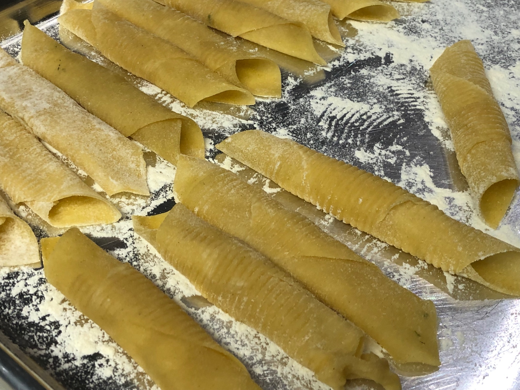 Fresh handmade Garganelli pasta resting on a flour-dusted tray